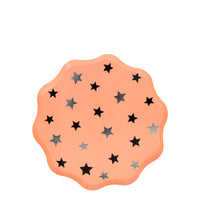 Soft orange party plates enhanced with a scalloped edge and lots of shiny silver stars .