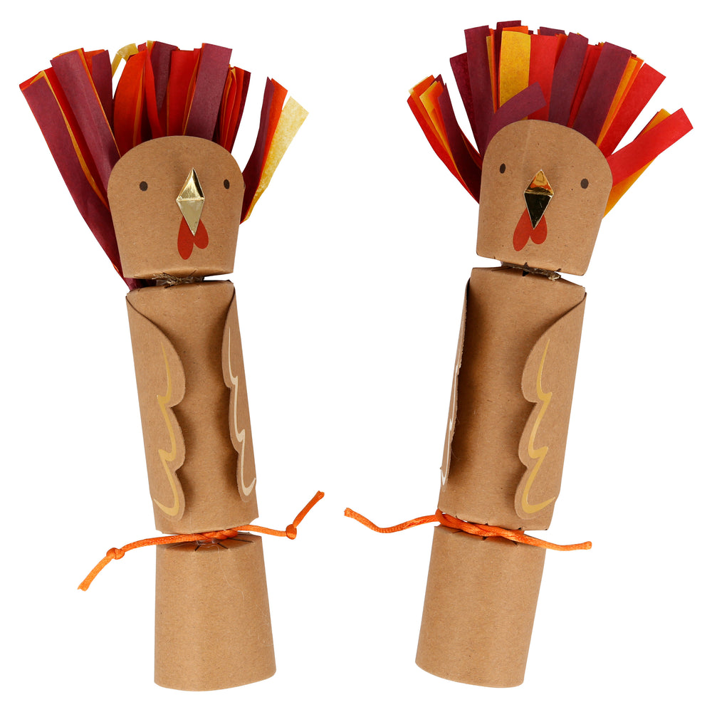 Thanksgiving themed crackers made of kraft paper with paper feather tail in fall colors, gold foil beak and details. Ends are tied off with an orange cord. Each cracker includes an etched wooden animal character either a badger, reindeer, squirrel, fox, rabbit or beaver and gold paper crown.