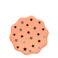 Soft orange party plates enhanced with a scalloped edge and lots of shiny silver stars . 