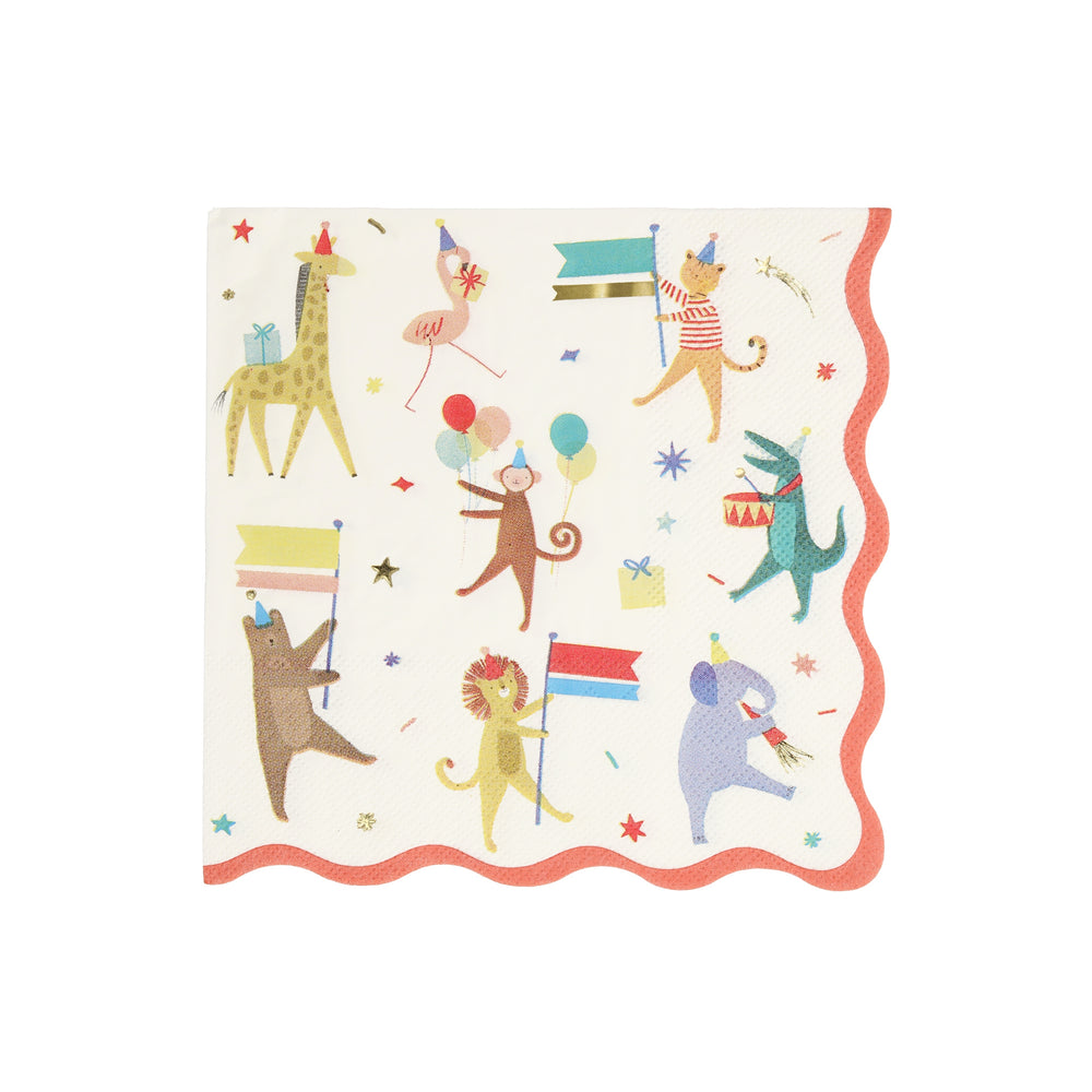 A square paper party napkin with scalloped edges, featuring a whimsical animal parade print on a white background. The design includes a alligator, giraffe, flamingo, monkey, bear, lion, and elephant holding flags and balloons, surrounded by confetti and gold foil stars. Red border