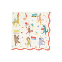 A square paper party napkin with scalloped edges, featuring a whimsical animal parade print on a white background. The design includes a alligator, giraffe, flamingo, monkey, bear, lion, and elephant holding flags and balloons, surrounded by confetti and gold foil stars. Red border