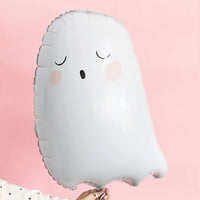 White ghost Mylar balloon being held by a woman with a white blouse with black stars photographed on a pink backdrop.