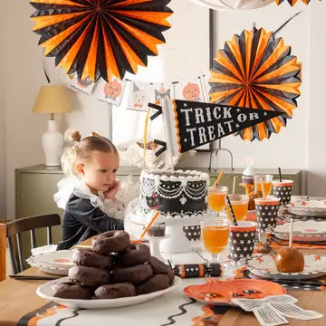 Party celebration featuring orange and black tissue paper party decor fans.