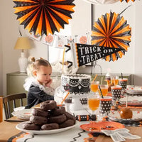Party celebration featuring orange and black tissue paper party decor fans.