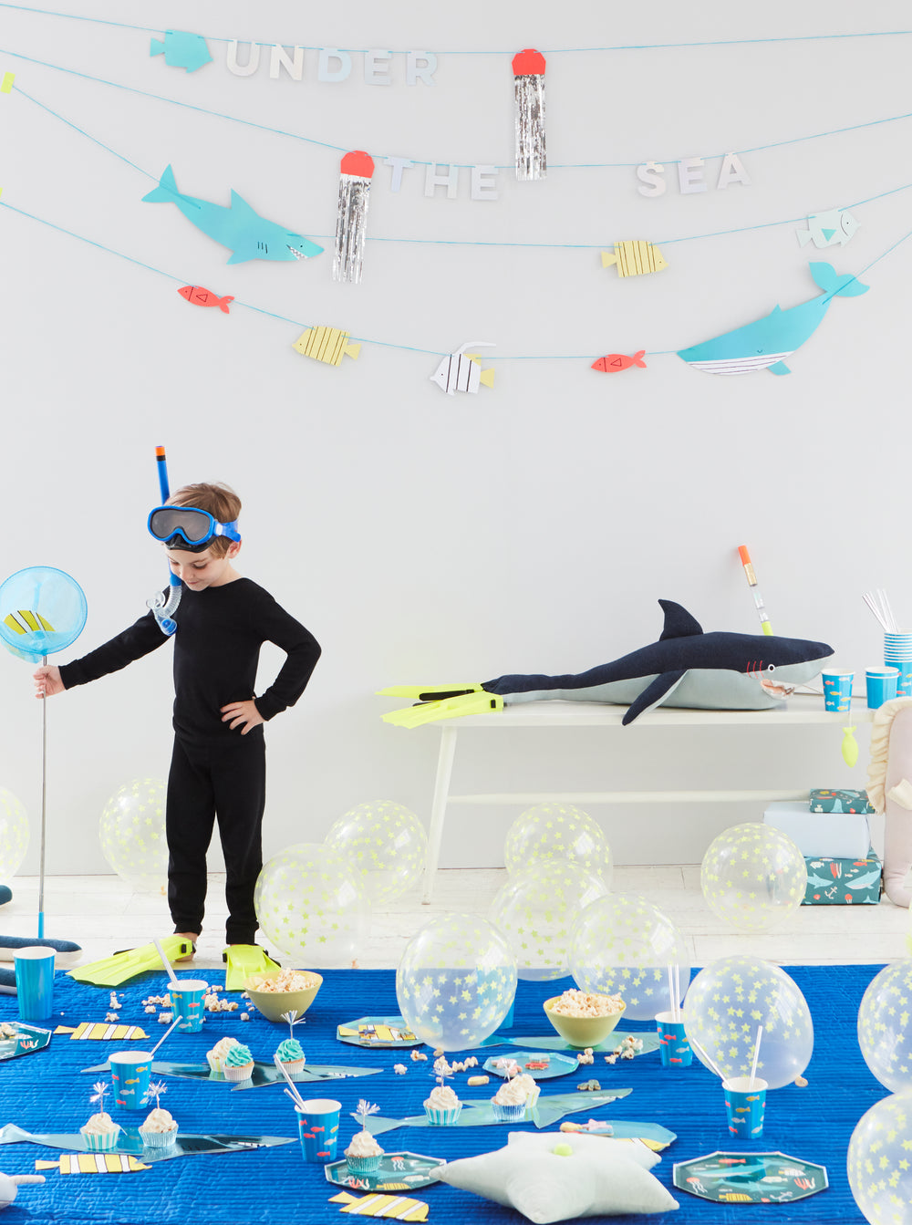 "under the sea" party theme set up including garland, party plates, cups and balloons.